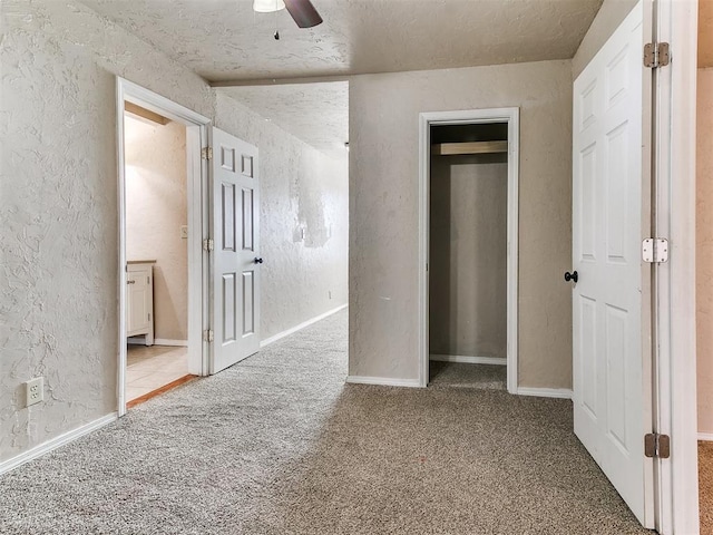 unfurnished bedroom featuring ceiling fan, baseboards, carpet flooring, and a textured wall