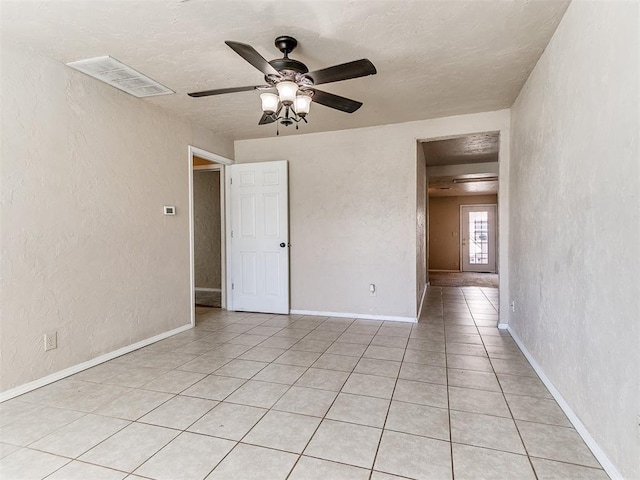 unfurnished bedroom with light tile patterned floors, baseboards, visible vents, and a textured wall