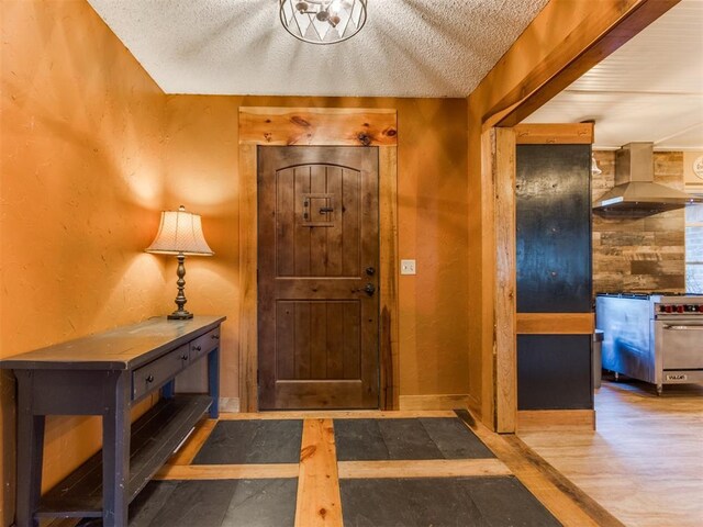 foyer with wood finished floors, a textured ceiling, and baseboards