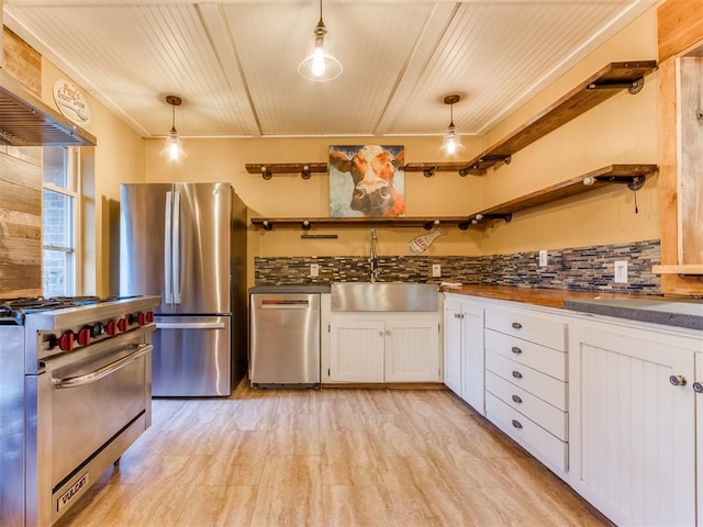 kitchen with stainless steel appliances, a sink, white cabinetry, dark countertops, and open shelves