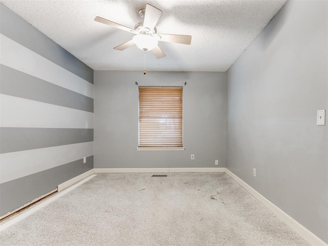 spare room featuring a ceiling fan, a textured ceiling, carpet floors, and baseboards