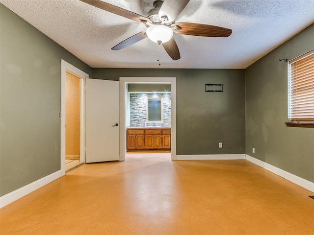 unfurnished room featuring concrete flooring, a textured ceiling, ceiling fan, and baseboards