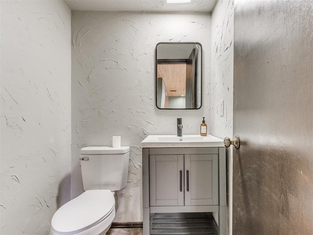 half bathroom with vanity and toilet