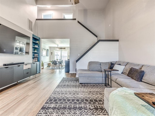 living room featuring visible vents, a towering ceiling, and wood finished floors