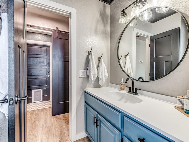 bathroom with a textured wall, wood finished floors, and vanity