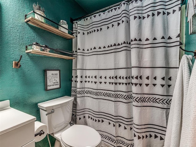 bathroom featuring a textured wall, vanity, and toilet