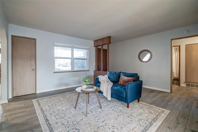 living area featuring visible vents, baseboards, and wood finished floors