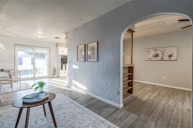 living room featuring light wood-style floors, arched walkways, and baseboards