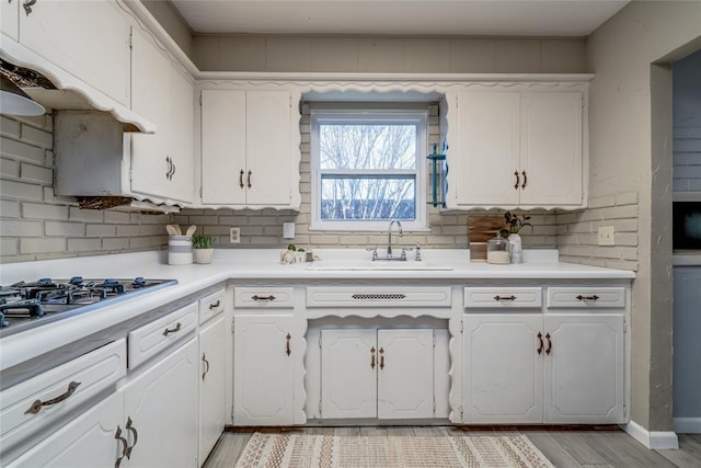 kitchen with light wood-style floors, light countertops, white cabinetry, and a sink