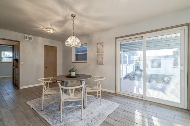 dining area with baseboards, visible vents, and wood finished floors