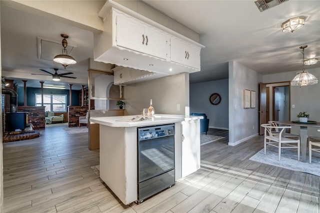 kitchen featuring black dishwasher, light countertops, visible vents, a wood stove, and white cabinets