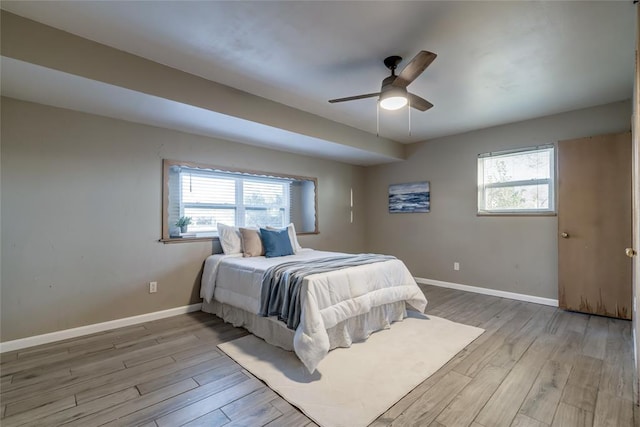 bedroom with multiple windows, wood finished floors, and baseboards