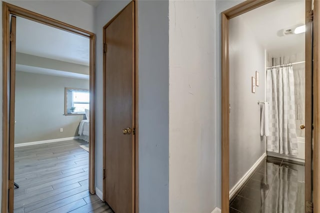 hallway featuring baseboards and wood finished floors