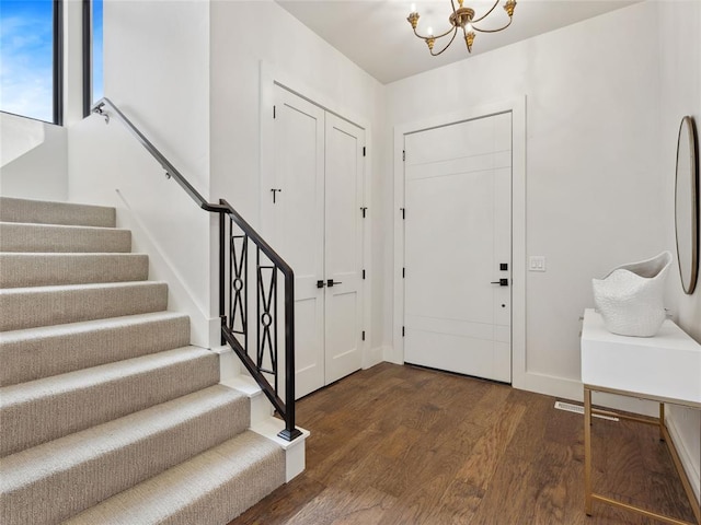 entryway with baseboards, a notable chandelier, stairway, and wood finished floors