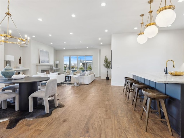 dining area with baseboards, a fireplace, wood finished floors, and recessed lighting