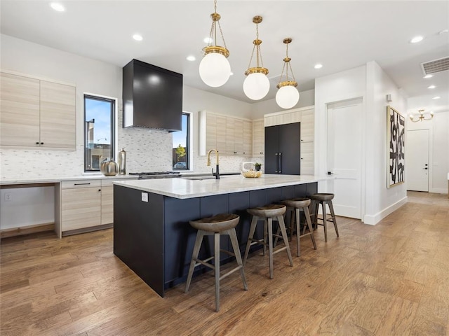 kitchen with a large island, visible vents, a sink, modern cabinets, and light wood-type flooring