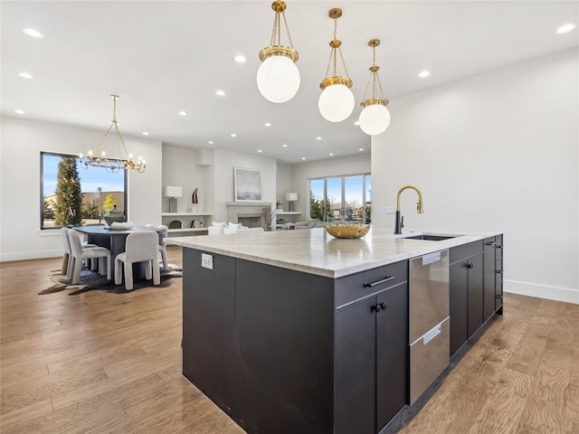 kitchen featuring pendant lighting, recessed lighting, light wood-style floors, a sink, and an island with sink