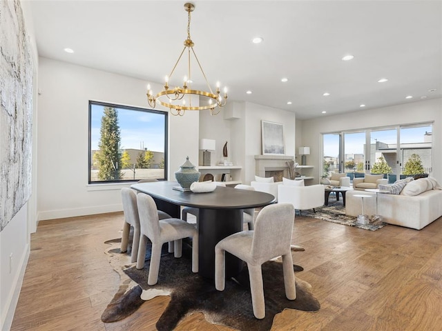 dining room with light wood-style floors, a fireplace, baseboards, and recessed lighting