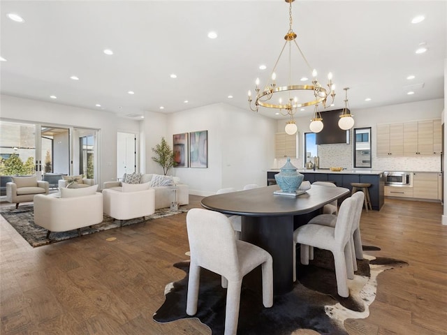 dining room featuring an inviting chandelier, baseboards, wood finished floors, and recessed lighting