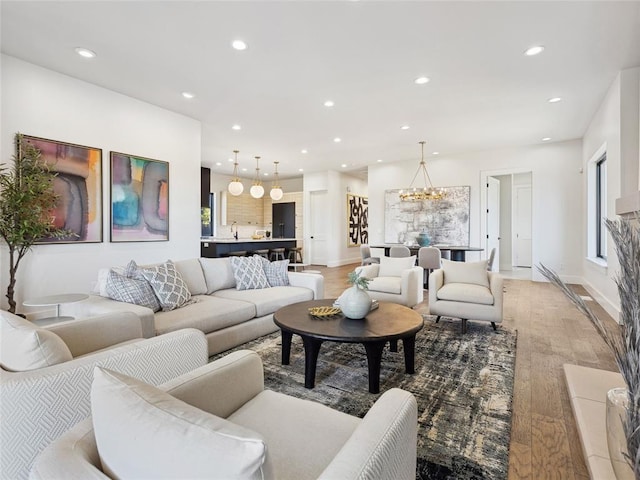 living room featuring a notable chandelier, light wood-style floors, and recessed lighting