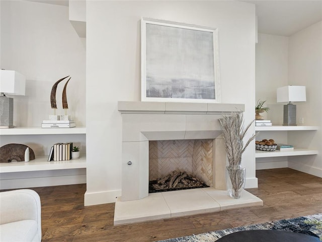 details with a tile fireplace, baseboards, and wood finished floors