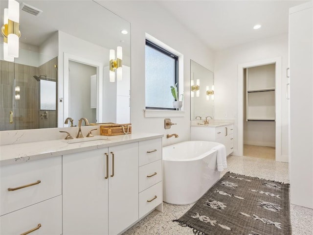 bathroom with two vanities, a stall shower, visible vents, and a sink