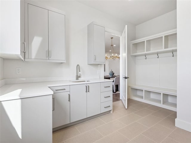 kitchen featuring light tile patterned floors, a notable chandelier, a sink, light countertops, and open shelves