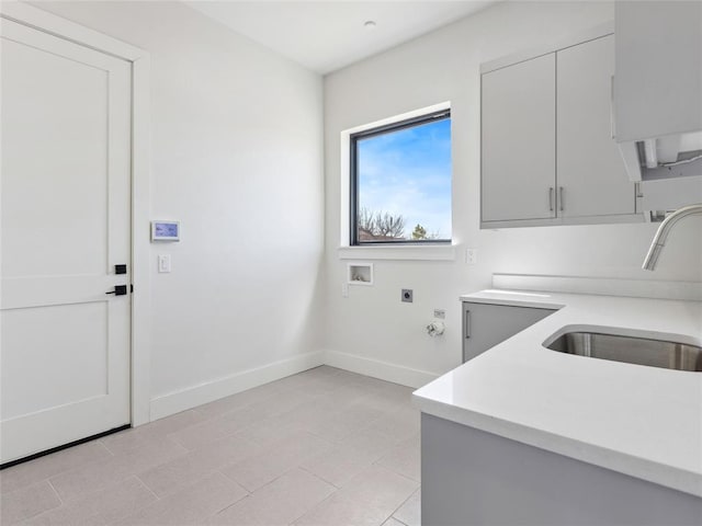 clothes washing area featuring hookup for a gas dryer, cabinet space, hookup for an electric dryer, a sink, and baseboards