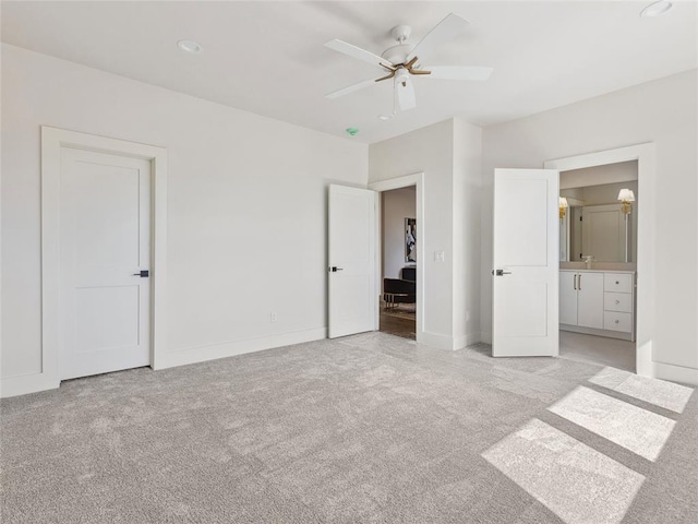 unfurnished bedroom featuring light carpet, ceiling fan, baseboards, and connected bathroom