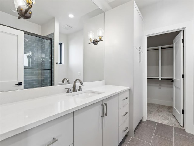 bathroom with a stall shower, baseboards, tile patterned floors, vanity, and recessed lighting