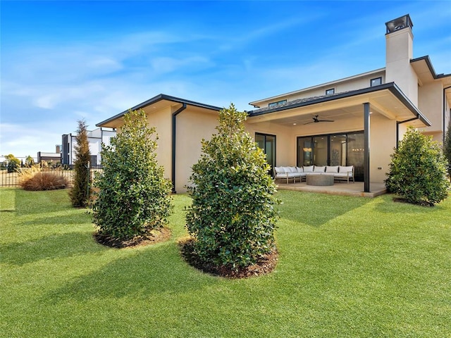 rear view of house with ceiling fan, a patio, outdoor lounge area, a yard, and stucco siding