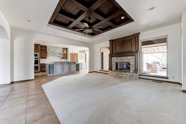 unfurnished living room with a fireplace, baseboards, coffered ceiling, and a ceiling fan