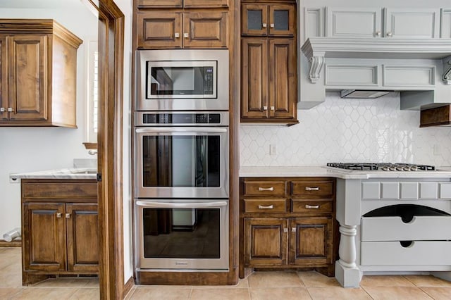 kitchen featuring appliances with stainless steel finishes, light countertops, decorative backsplash, and light tile patterned floors