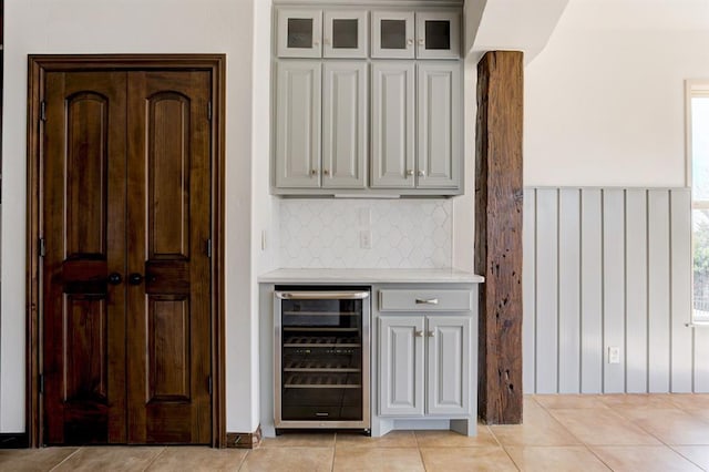 bar with beverage cooler, decorative backsplash, and light tile patterned floors