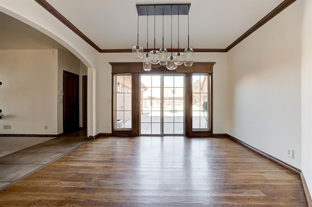 unfurnished room featuring arched walkways, wood finished floors, and ornamental molding