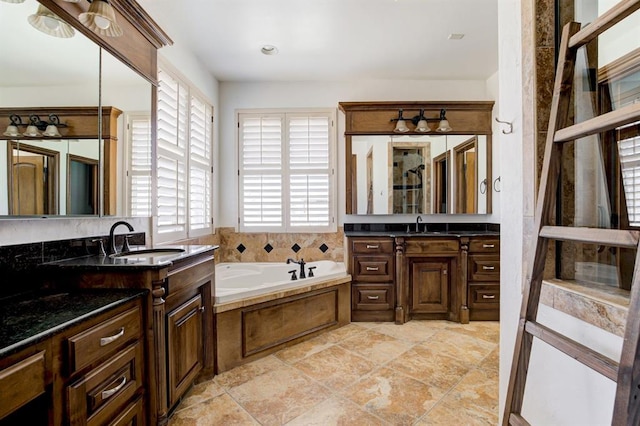 full bathroom with two vanities, a garden tub, and a sink