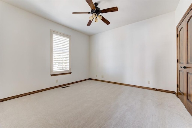 spare room with a ceiling fan, light carpet, visible vents, and baseboards