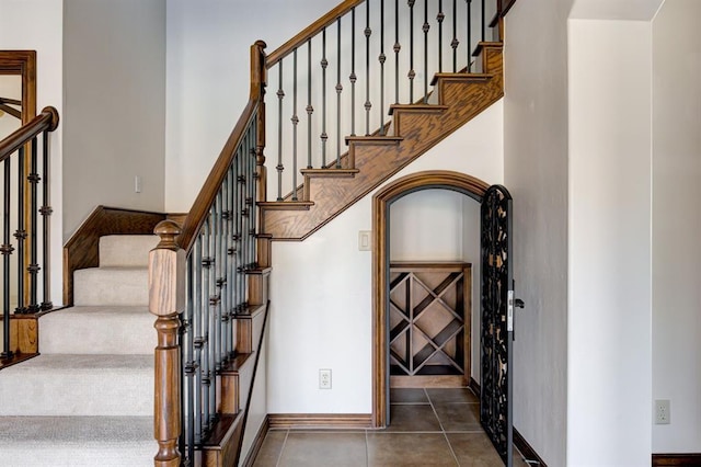 stairs featuring arched walkways, baseboards, and tile patterned floors