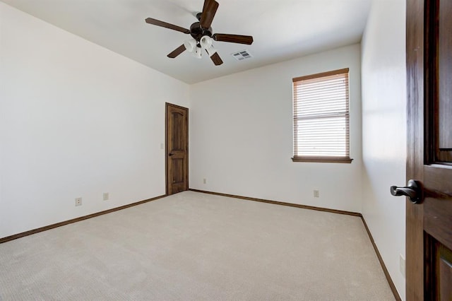 spare room with baseboards, ceiling fan, visible vents, and light colored carpet