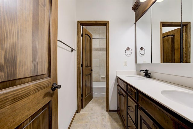 full bathroom featuring a sink, baseboards, and double vanity