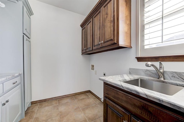 clothes washing area with cabinet space, light tile patterned floors, a sink, hookup for a washing machine, and electric dryer hookup