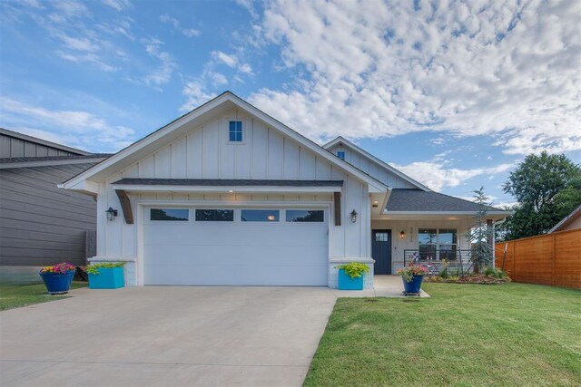 view of front of home with board and batten siding, an attached garage, fence, and a front yard