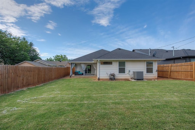 back of house featuring a yard, central AC, a fenced backyard, and roof with shingles