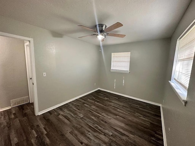 unfurnished room featuring dark wood-style flooring, visible vents, ceiling fan, a textured ceiling, and baseboards