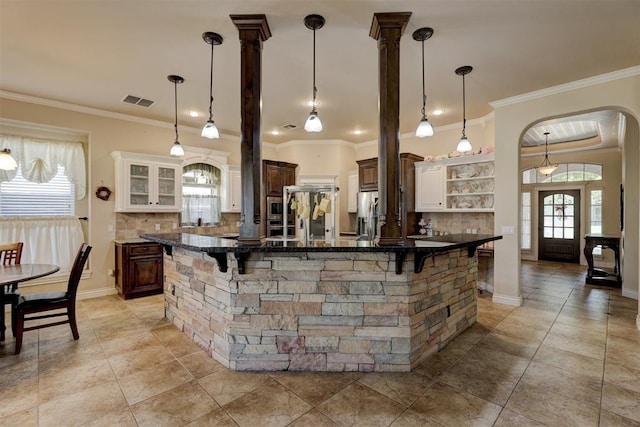 kitchen with a breakfast bar area, stainless steel appliances, a large island, open shelves, and crown molding