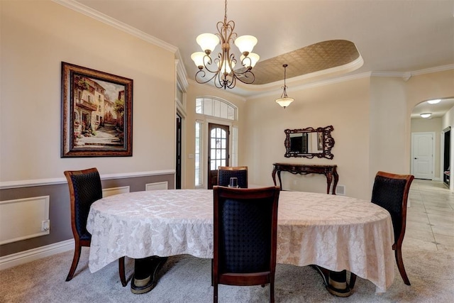 dining space featuring ornamental molding, arched walkways, light carpet, and an inviting chandelier