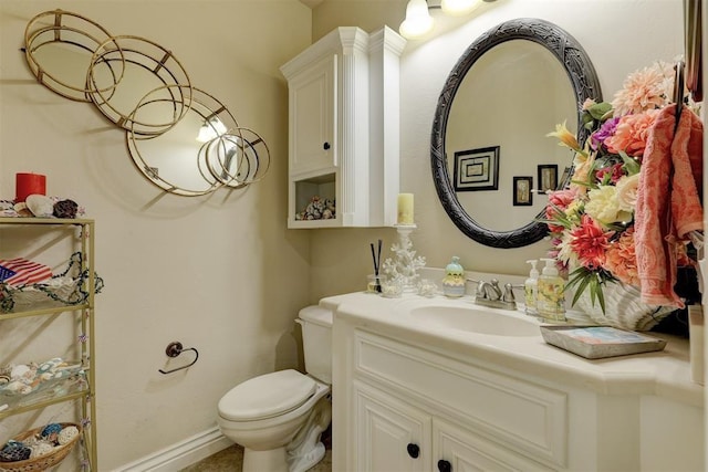 bathroom featuring toilet, vanity, and baseboards