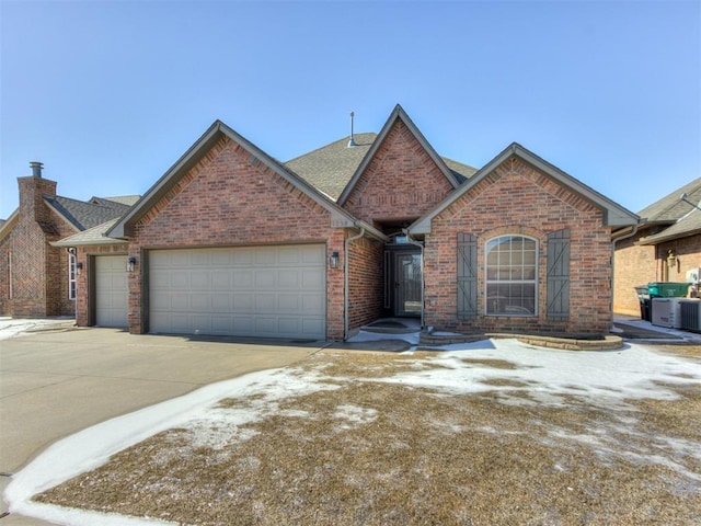 view of front facade featuring a garage, driveway, roof with shingles, and brick siding