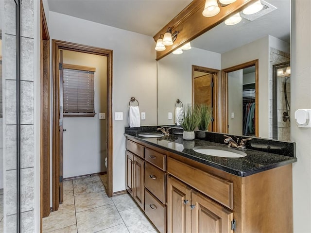 bathroom with tile patterned flooring, a walk in closet, a sink, and double vanity