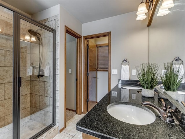 bathroom featuring double vanity, a shower stall, a sink, and tile patterned floors